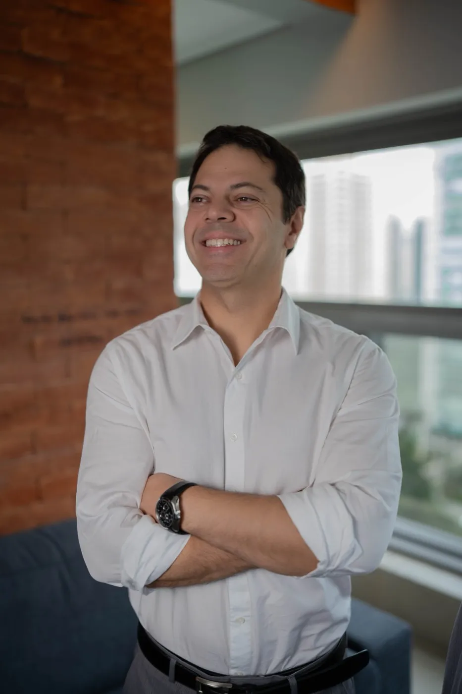 Dr. Flavio Pestilla Esperidião, urologista, sorrindo de braços cruzados em seu consultório