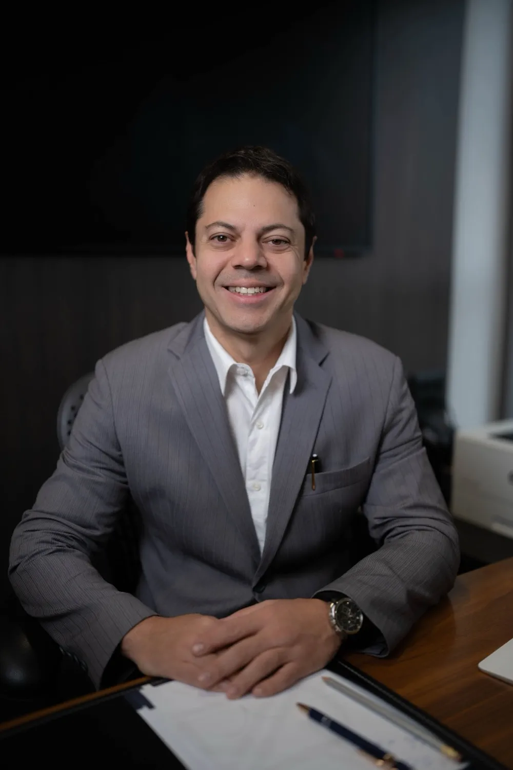 Dr. Flavio Pestilla Esperidião, urologista, sorrindo à mesa de seu consultório